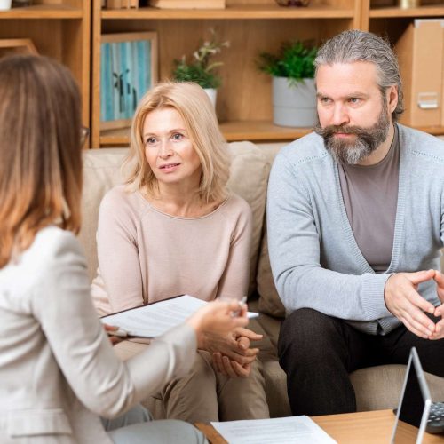 mature-man-and-his-wife-sitting-on-sofa-and-consulting-with-real-estate-agent (1)